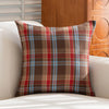 Plaid-Kissenbezug in Braun, Rot und Blau auf weißem Sofa.