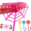 A hand holds a pink stretchy spider web climbing toy with a long stick and multiple strands.