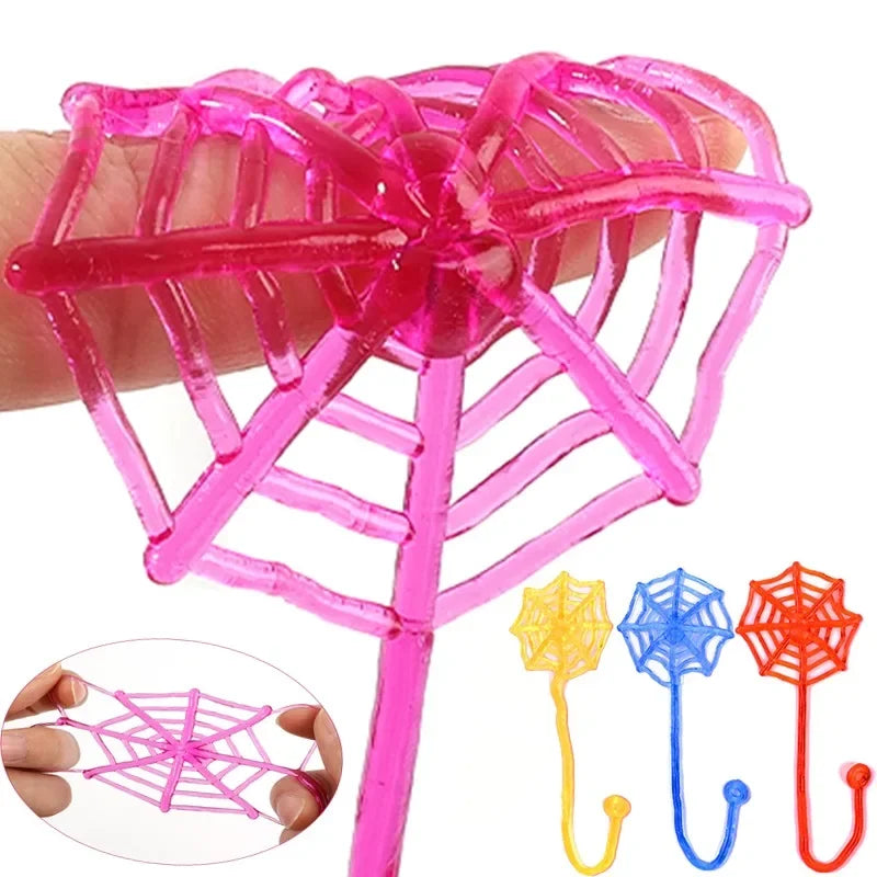 A hand holds a pink stretchy spider web climbing toy with a long stick and multiple strands.