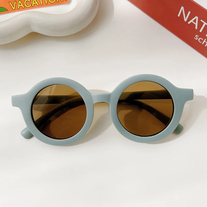 Light blue sunglasses with brown lenses resting on a white surface.
