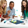 Three people laughing while playing a blue and yellow bounce ball tabletop game on a white table.