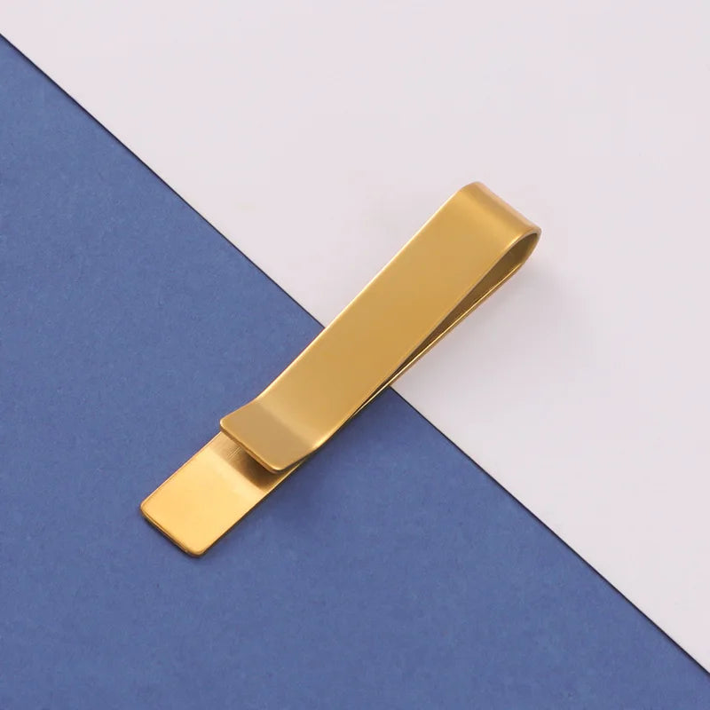 A gold metal tie clip lying diagonally on a blue and white background.