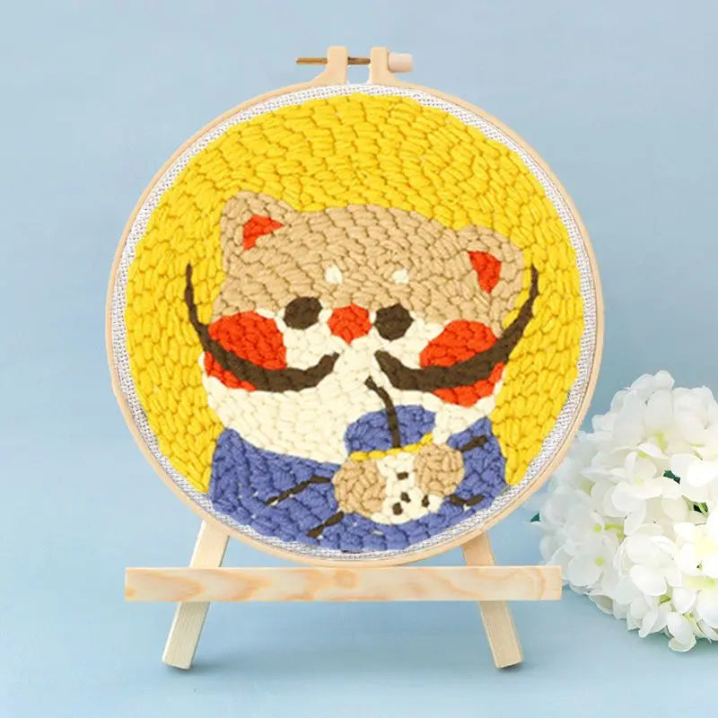Bordado de punch needle colorido con cara de oso linda, pelaje naranja y marrón con rayas.