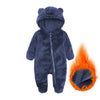 A dark blue fuzzy baby fleece hooded romper with a zipper, shown next to a small flame.