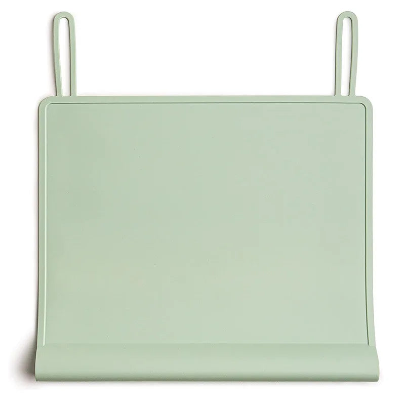 A light green silicone feeding placemat with a teething edge and hanging loops.