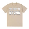 En lys beige t-shirt med teksten YOU MIGHT BE DRUNK i grå skrift.