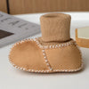 A pair of tan suede leather winter booties with a soft fur lining displayed on a white surface.