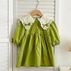 A lime green kids princess dress with floral embroidery and white lace trim hanging on a wooden hanger.