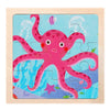 A colorful wooden puzzle featuring a pink, textured sea anemone and small fish in blue water.