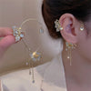 Gold butterfly zircon ear cuff with dangling gold tassels worn on a woman's ear.