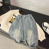 Light wash denim jeans and a cream sweatshirt laid out on a dark surface.