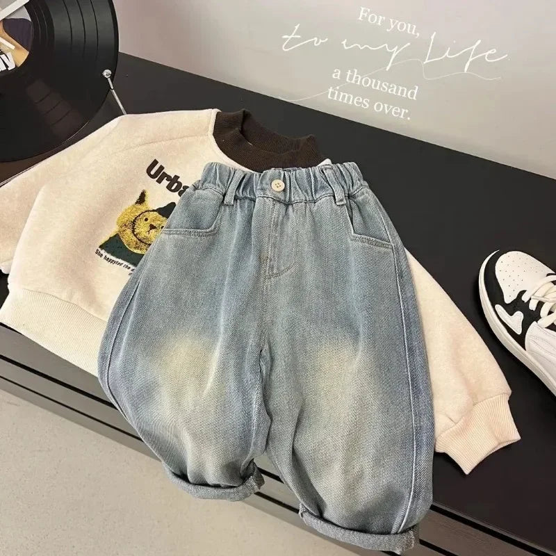 Light wash denim jeans and a cream sweatshirt laid out on a dark surface.