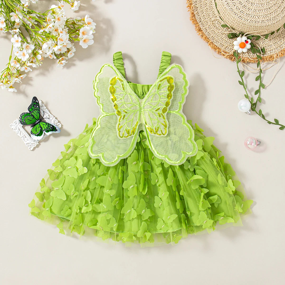 A light green tulle dress with a large butterfly appliqué and green suspenders, set against a neutral background.
