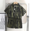 A dark green and black abstract print shirt is displayed on a hanger against a white background.