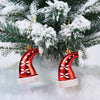 A set of two red and white candy cane Christmas tree ornaments hanging on a snowy green pine branch.