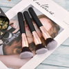 Three professional makeup brushes with gold ferrules and grey bristles displayed on a white background.