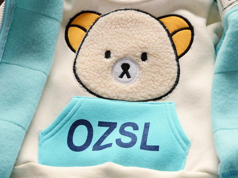 A white fleece pajama top featuring a cute bear face and a light blue chest patch with the text OZSL.
