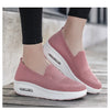 Un par de zapatos de caminar rosados con air cushion y plataforma blanca en una superficie de madera.