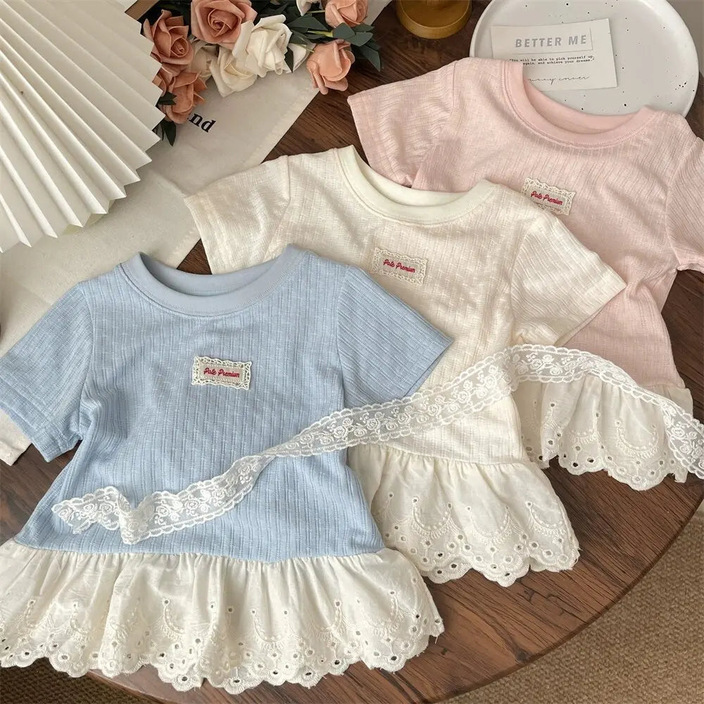 A collection of pink and blue girls cotton lace hem short sleeve tees displayed on a wooden surface.