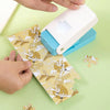 Hands are assembling a DIY puzzle maker tool for custom crafts and scrapbooking on a light green surface.