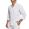 A man wearing a white long sleeve button-down shirt and light pants.