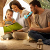 A mother and son are reading a story together using a kids projector flashlight and story cards on a soft rug.