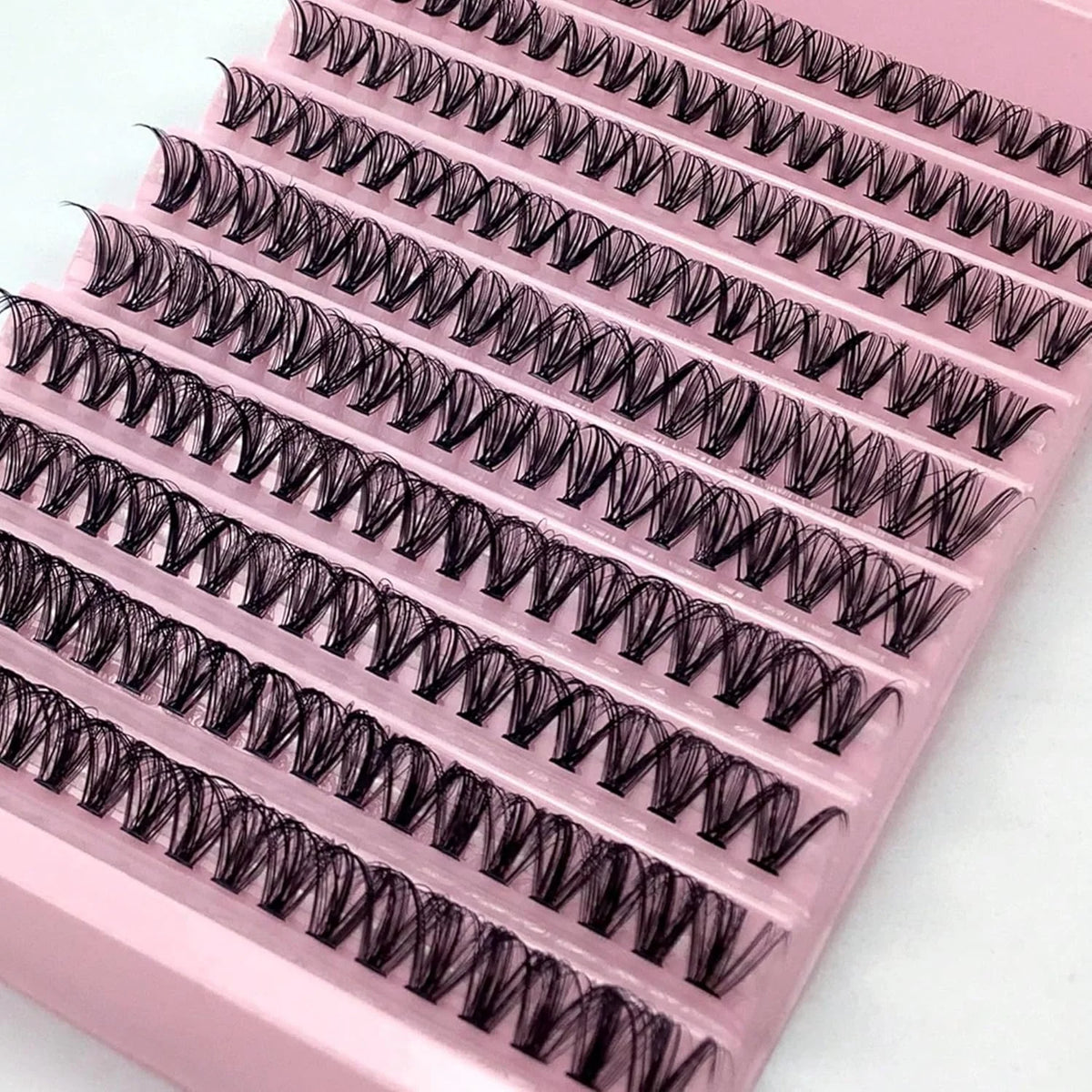 A pink plastic case containing ten pairs of ultra-dense false eyelashes with tightly curled synthetic fibers.