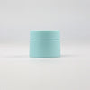 A light blue refillable travel face cream jar with a white lid, shown against a white background.