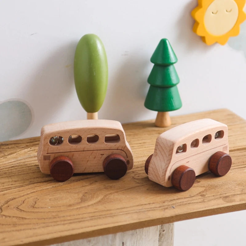 A hand-pushed wooden cart toy for toddlers with a green handle and a small green tree decoration.