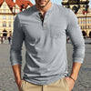 A man wearing a light gray long-sleeve casual shirt with a chest pocket and tan pants.