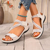 Sandalias romanas de cuña beige para mujer, usadas con jeans y pulsera de cuentas azul.