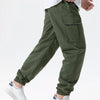 A man wearing olive green cargo joggers and white sneakers, showing the fit of the pants.