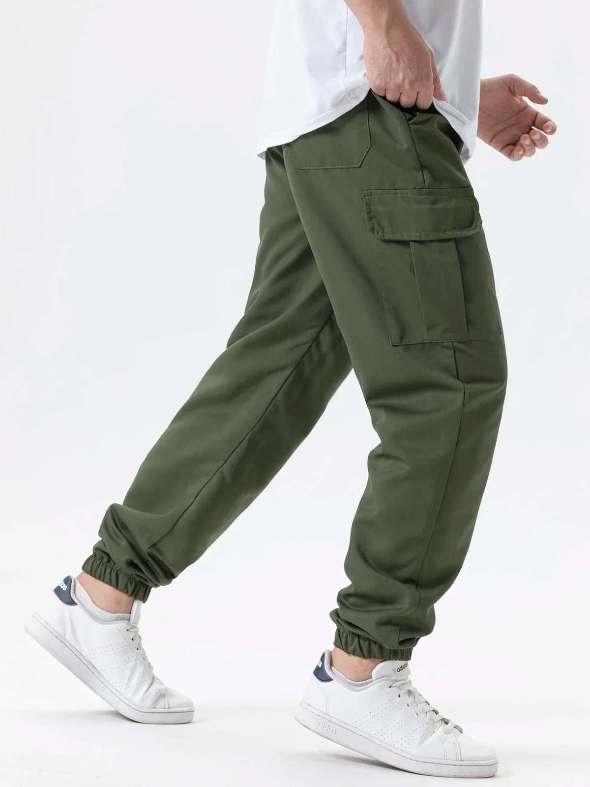 A man wearing olive green cargo joggers and white sneakers, showing the fit of the pants.