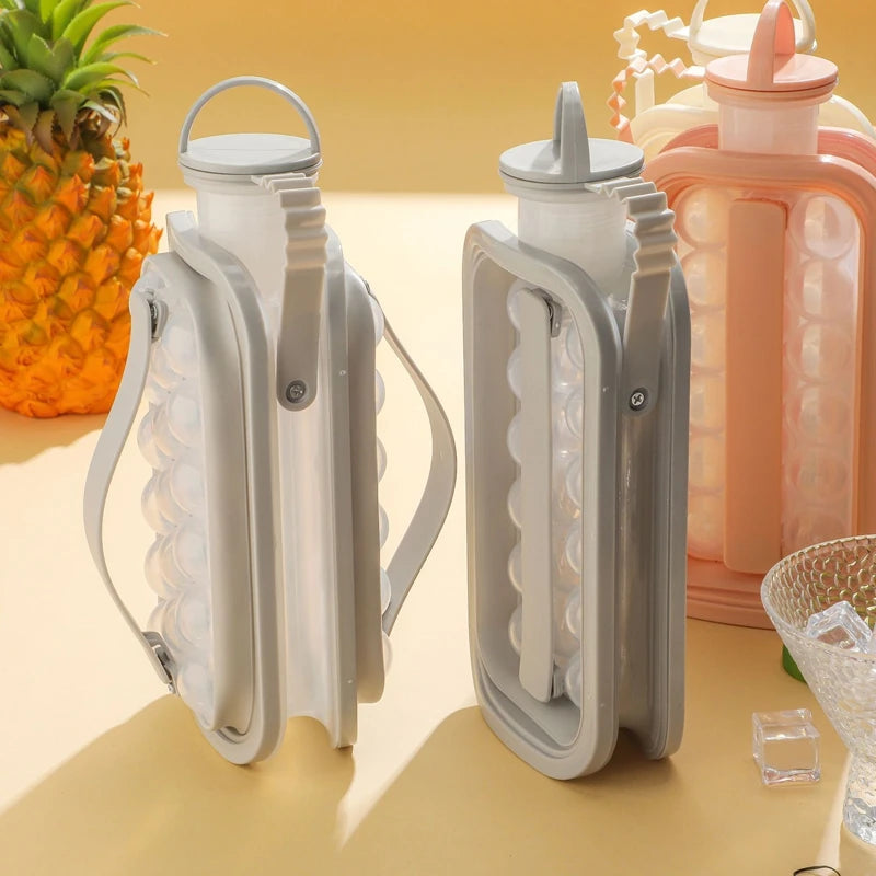 A set of two portable ice cube trays and a pink water bottle mold are displayed on a light surface.