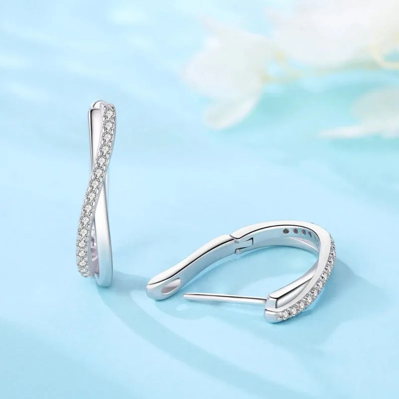Aros de aro retorcidos de plata esterlina con circonita sobre fondo azul claro.