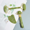 Juego de rodillo de jade y herramientas gua sha en verde claro y dorado, sobre fondo blanco.