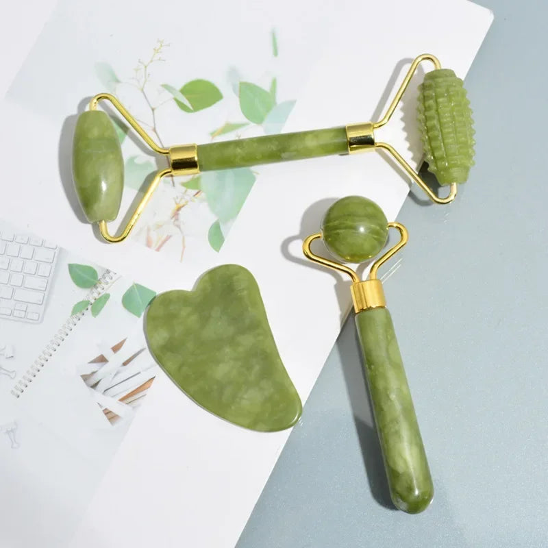 Juego de rodillo de jade y herramientas gua sha en verde claro y dorado, sobre fondo blanco.