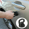 Une main utilise un débosselleur à ventouse noir pour enlever une bosse sur la carrosserie d'une voiture.