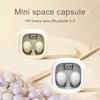 A white mini space capsule charging case for wireless earbuds, shown next to a pile of light-colored spherical objects.