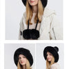 A woman models a beige knitted hooded scarf with black fur trim and a light jacket.
