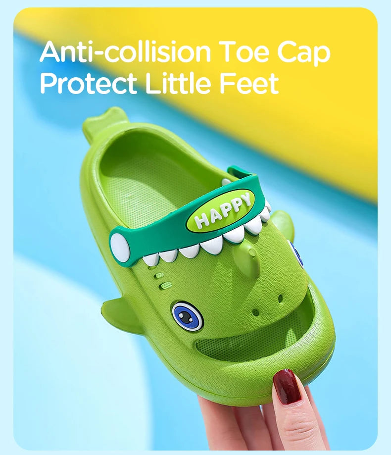 A green kids clog sandal with a happy tooth design is held by a hand.