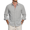 A man wearing a light gray long sleeve button-down shirt and a silver necklace.