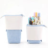 Trousse rétractable blanche et bleu clair avec un dessus en plastique transparent montrant divers outils d'écriture à l'intér
