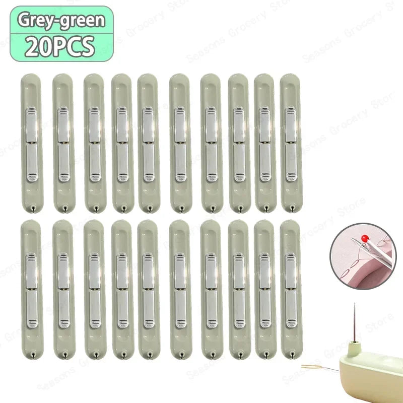 A set of twenty grey-green needle threaders and seam rippers for sewing projects.