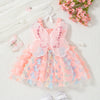 A pink butterfly tulle dress for a baby girl displayed on a white surface with pink flowers and beads.