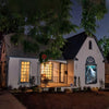 A white house facade decorated with spooky Halloween window clings featuring a ghost and haunted house theme.