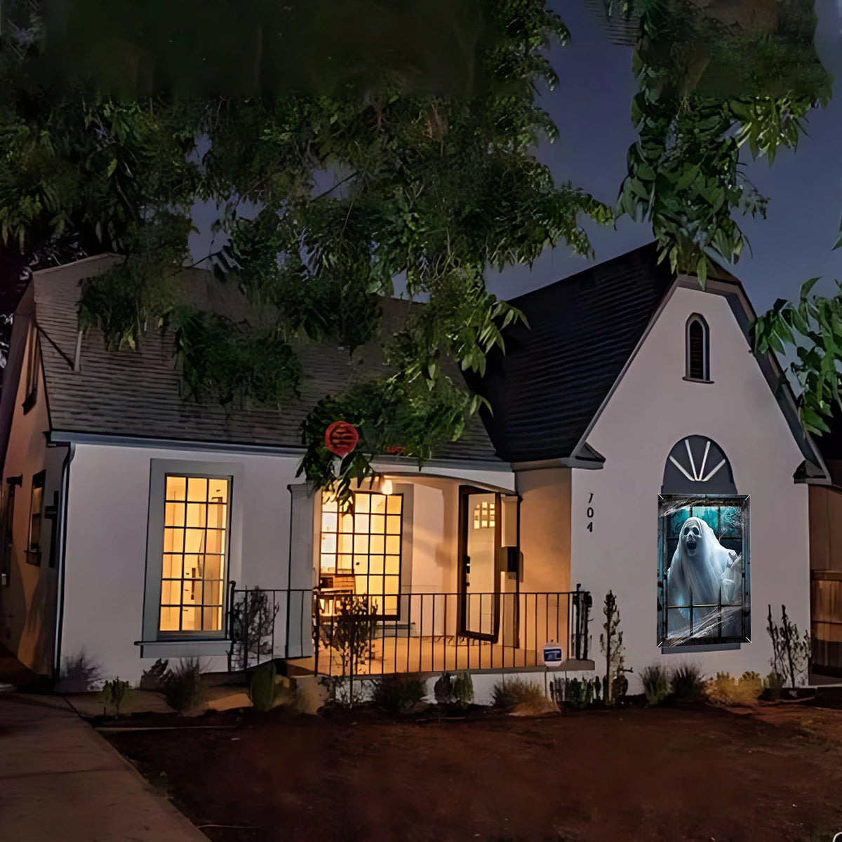 A white house facade decorated with spooky Halloween window clings featuring a ghost and haunted house theme.
