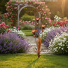 Hagescene med flammet kobberkallaliljestake med vindklokker blant fargerike blomster og grønt