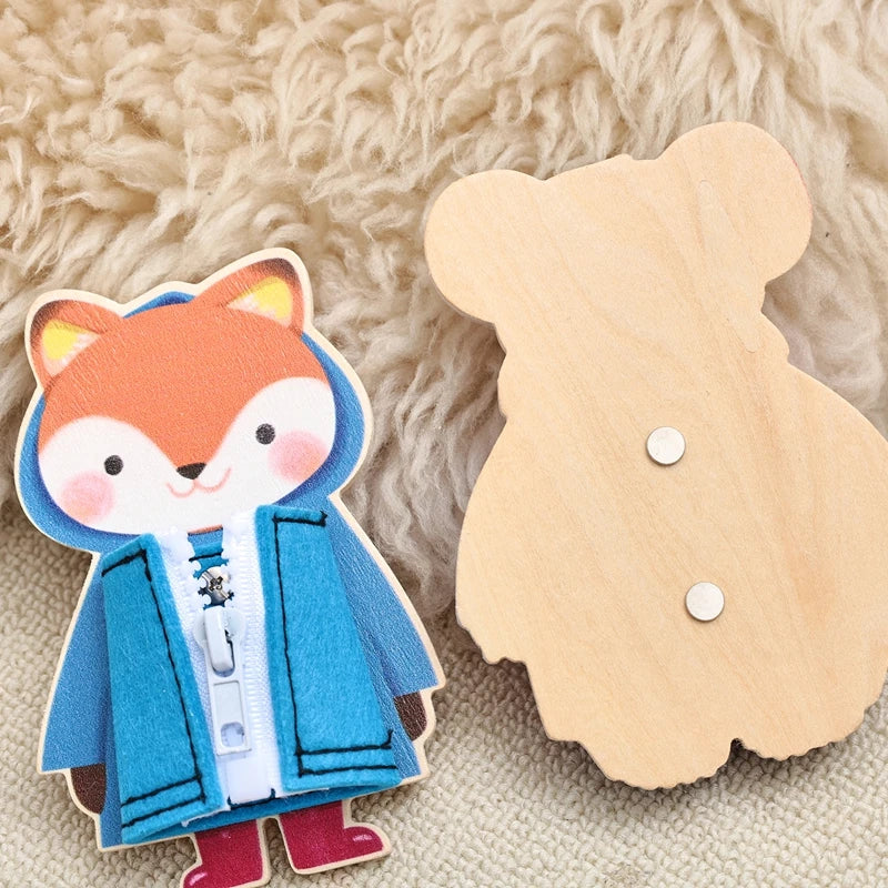 A wooden busy board featuring a fox character and clothing items for children's fine motor practice.