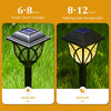 A black solar garden path light with a warm glow is shown under direct sunlight and during nighttime lighting.